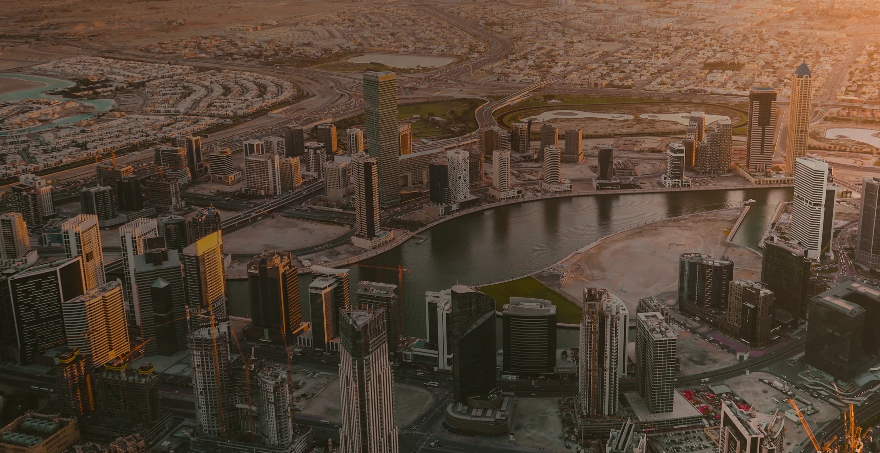 Aerial view of Dubai's Business Bay towers along the water canal at sunset
